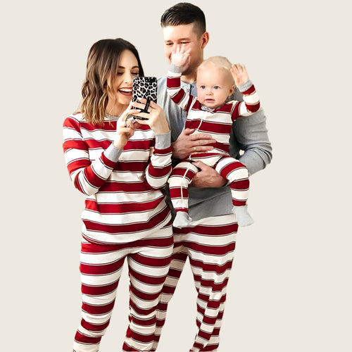 Family in matching red and white striped pajamas in a living room.