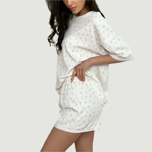Woman wearing a white nightgown with floral patterns in a bedroom setting.